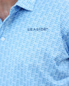 Close-up of a light blue dachshund patterned polo shirt with 'SEASIDE' embroidered on the chest, worn by a model.