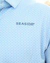 Close-up of a light blue coleman pavilion patterned button-down shirt with 'SEASIDE' embroidered in navy on the chest.