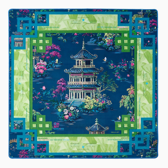 A square mahjong mat featuring an intricate Chinese landscape print with a central pagoda, pink cherry blossoms, and a green border, displayed flat against a white background.