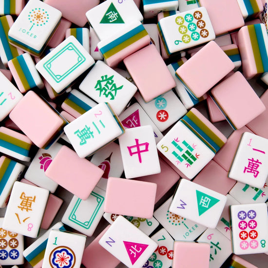A pile of Mahjong tiles in pastel colors, including pink, white, green, blue, and yellow, with Chinese characters and traditional symbols visible on the faces of the tiles.