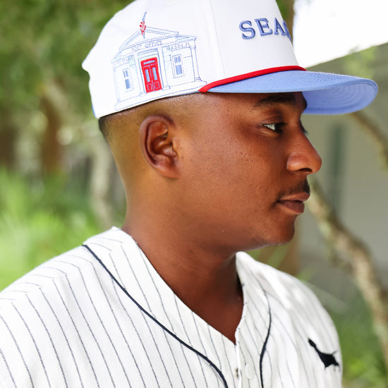 Side view showing Seaside Post Office illustration on white five-panel hat