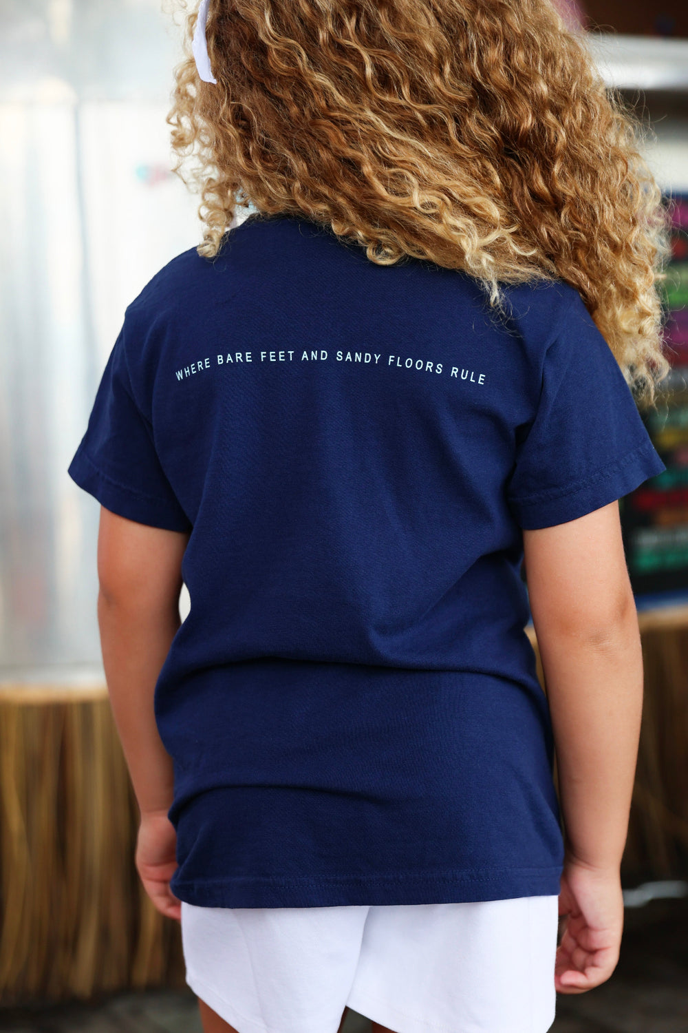 Youth Navy Blue Colors of Seaside Rainbow Tee Back with tagline "where bare feet and sandy floors rule"