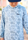 Person wearing a blue camouflage hoodie with a brand logo on a blurred background