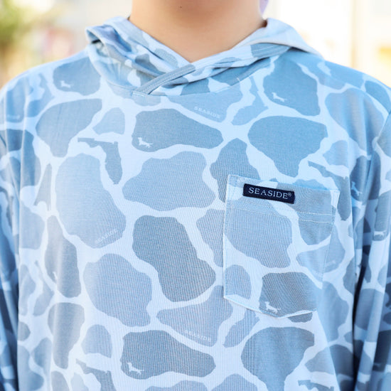 Blue patterned hoodie with a seaside logo on a blurred background