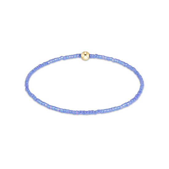 A delicate beaded bracelet in light blue with a small gold bead accent at the top, displayed on a clean white background.