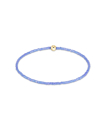 A delicate beaded bracelet in light blue with a small gold bead accent at the top, displayed on a clean white background.