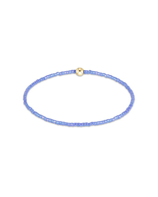A delicate beaded bracelet in light blue with a small gold bead accent at the top, displayed on a clean white background.