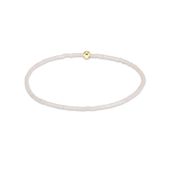 A delicate beaded bracelet in a translucent white or milky white material, featuring a single small gold bead accent at the top, shown on a plain white background.
