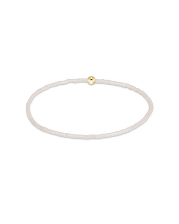 A delicate beaded bracelet in a translucent white or milky white material, featuring a single small gold bead accent at the top, shown on a plain white background.