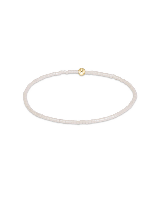 A delicate beaded bracelet in a translucent white or milky white material, featuring a single small gold bead accent at the top, shown on a plain white background.