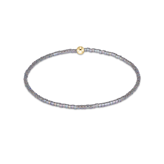 A delicate beaded bracelet with iridescent gray-blue beads and a small gold clasp, shown on a plain white background.