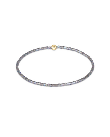 A delicate beaded bracelet with iridescent gray-blue beads and a small gold clasp, shown on a plain white background.