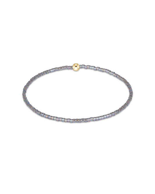 A delicate beaded bracelet with iridescent gray-blue beads and a small gold clasp, shown on a plain white background.