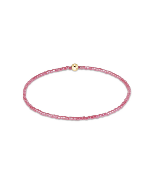 A delicate pink beaded bracelet with a small gold bead accent at the clasp, displayed on a clean white background.